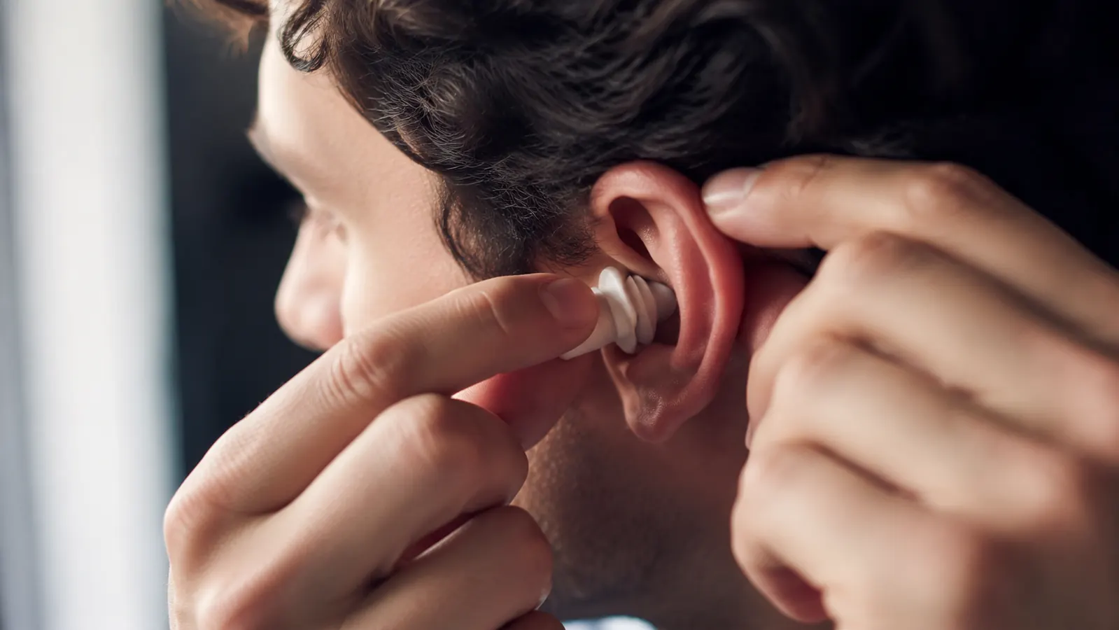 Hands gently pressing a small earplug into an ear before the show begins